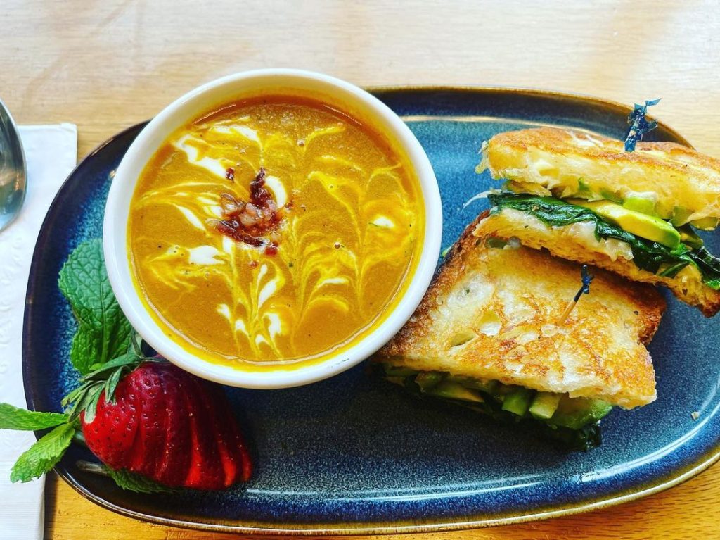 Image of carrot ginger soup and a perfectly browned grilled cheese sandwich.