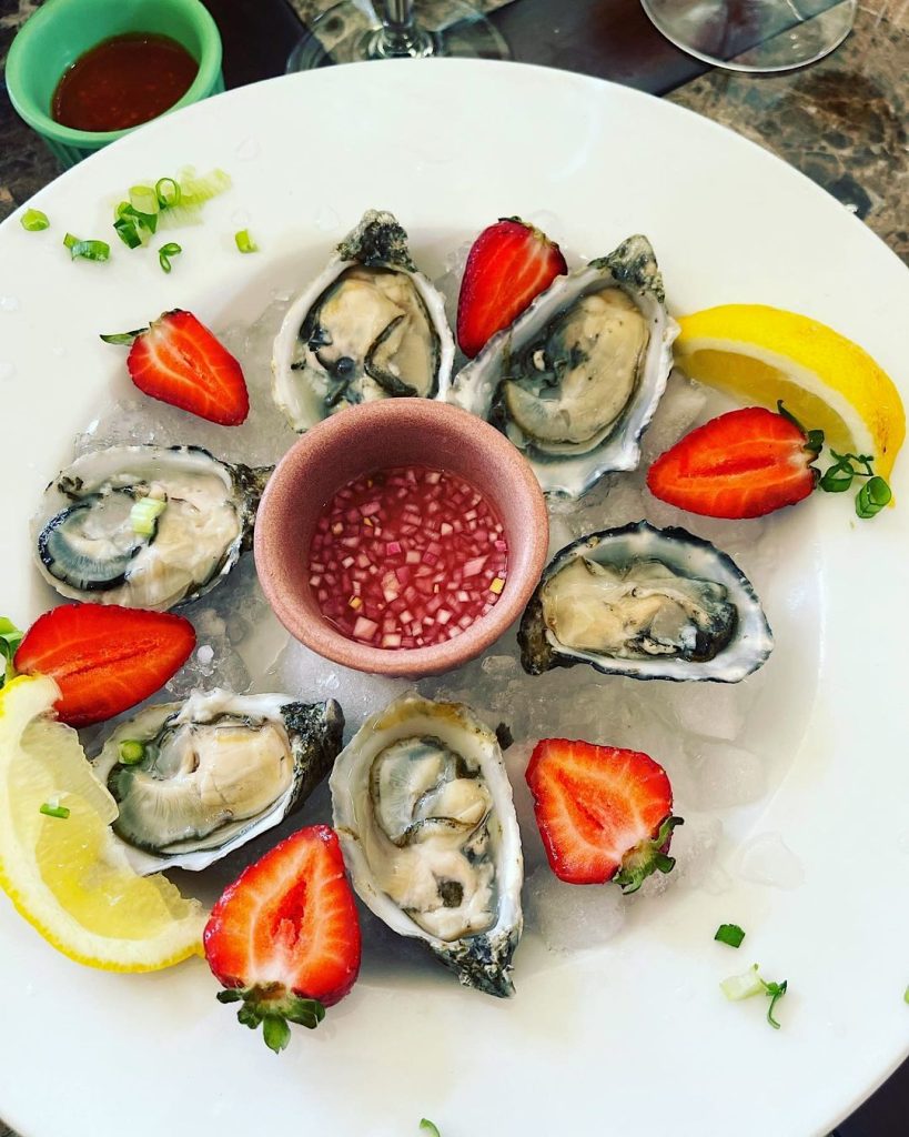 Fresh oysters with lemon wedges and halved bright red strawberries
